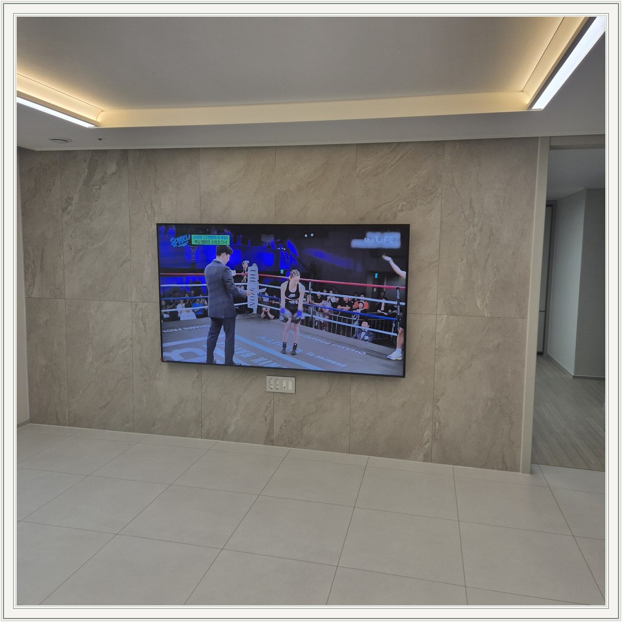 돌무늬 패널과 대형 TV / TV 아래 콘센트 패널이 드러나는 구도입니다