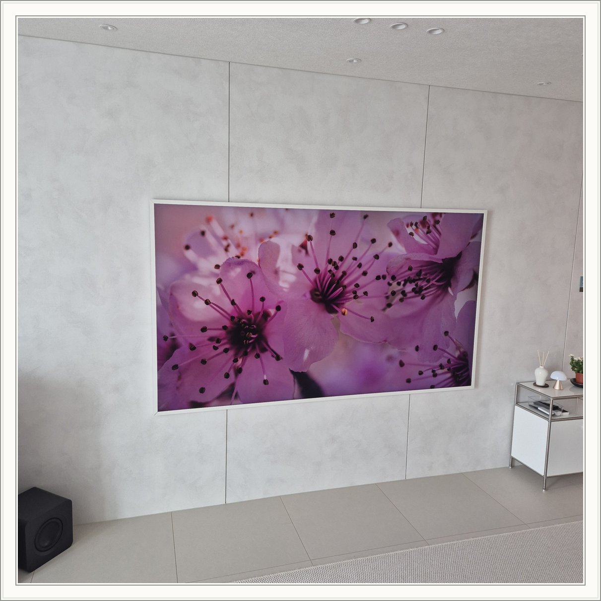 꽃 화면이 나오는 흰색 프레임 TV / 밝은 패널 위 흰 테두리와 꽃 영상의 색 대비가 큽니다