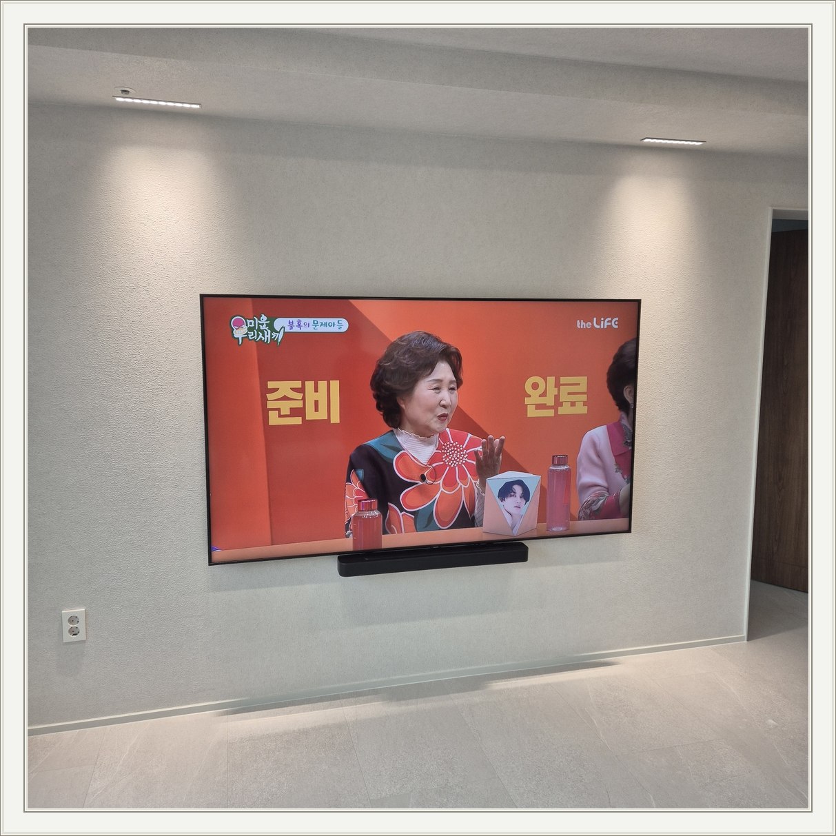 조명이 비추는 미색 벽과 사운드바 / 사운드바와 벽면의 간격이 한눈에 들어옵니다