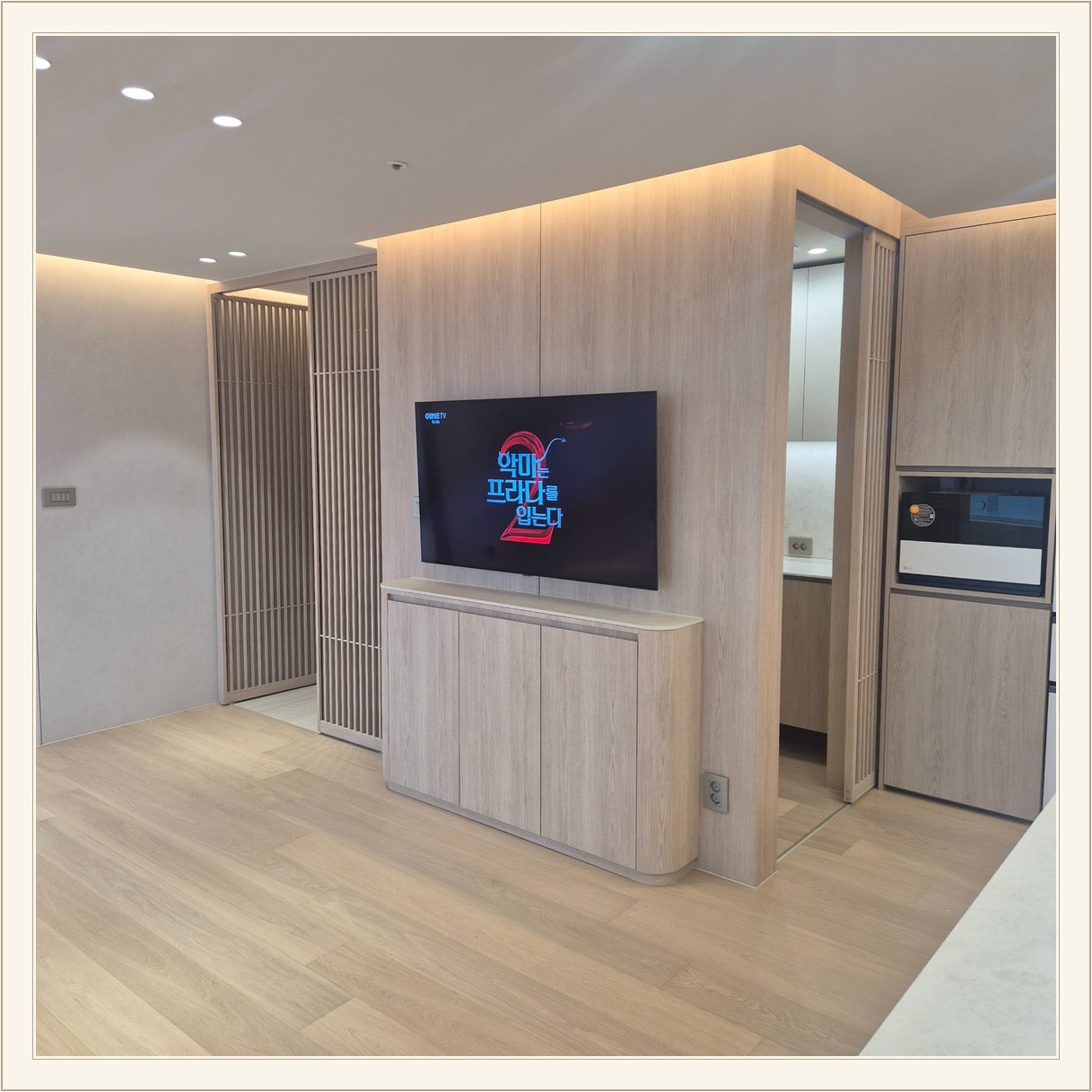 세로 원목 패널 위에 걸린 TV와 수납장 / 격자 형태 파티션을 끼고 TV가 놓인 위치를 확인할 수 있습니다