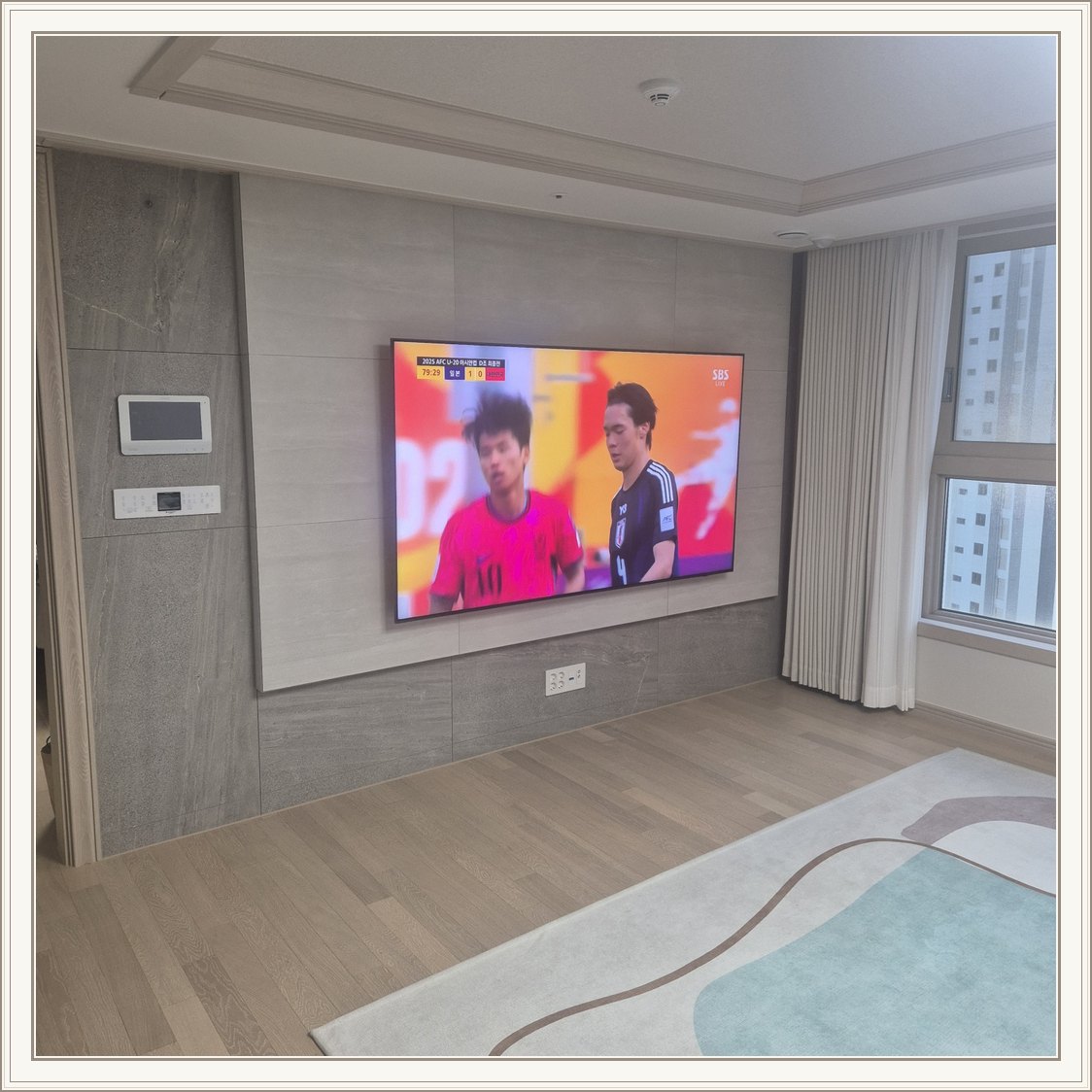 밝은 회색 아트월과 시청 공간 / 밝은 몰딩과 TV 아래 전원 위치가 같이 나타납니다