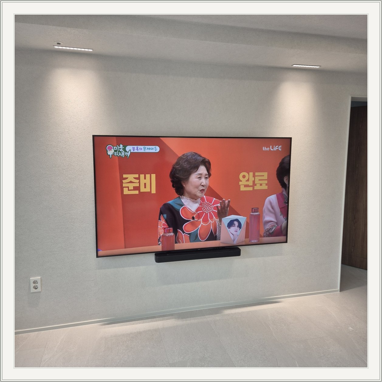 조명이 비추는 미색 벽과 사운드바 / 사운드바와 벽면의 간격이 한눈에 들어옵니다