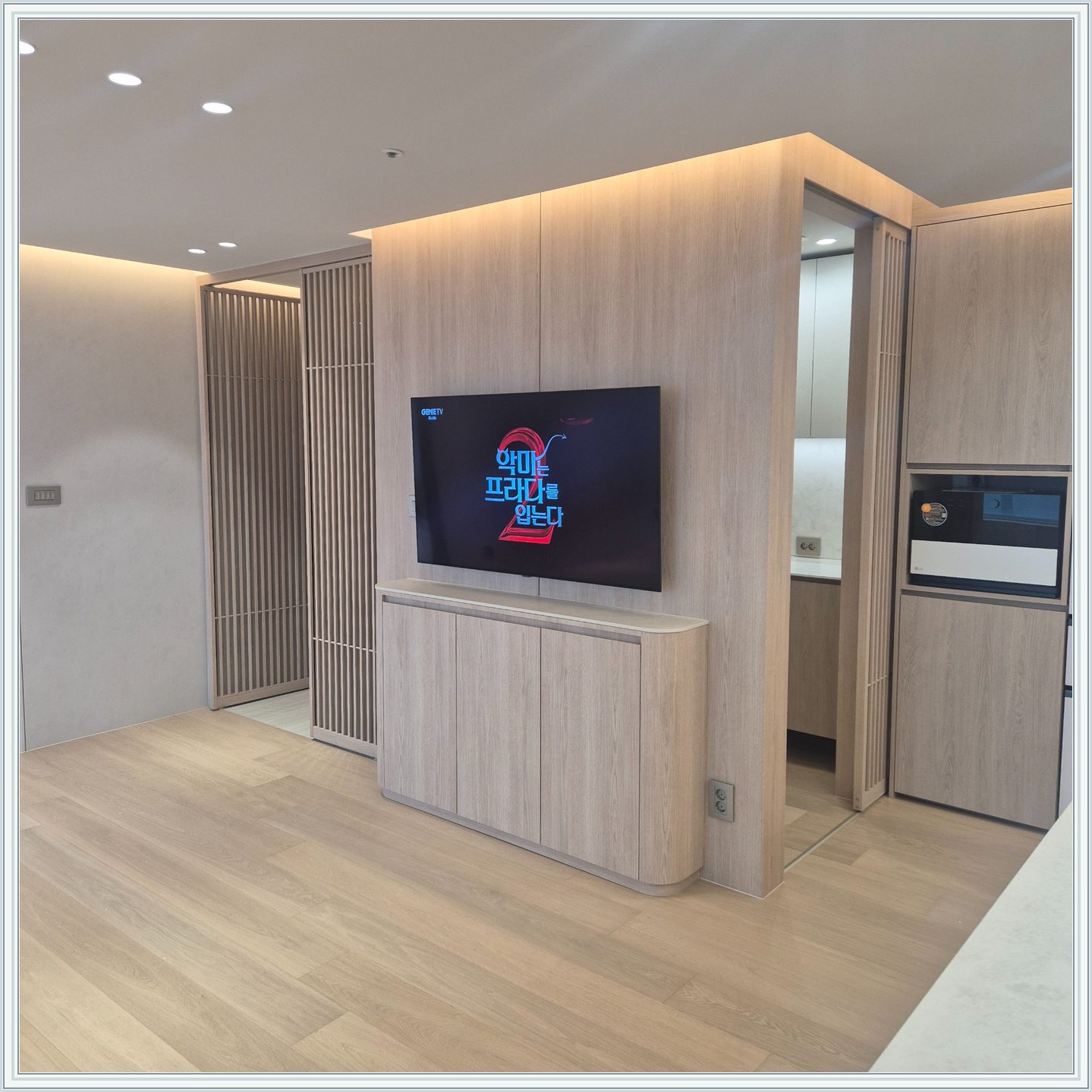 세로 원목 패널 위에 걸린 TV와 수납장 / 격자 형태 파티션을 끼고 TV가 놓인 위치를 확인할 수 있습니다