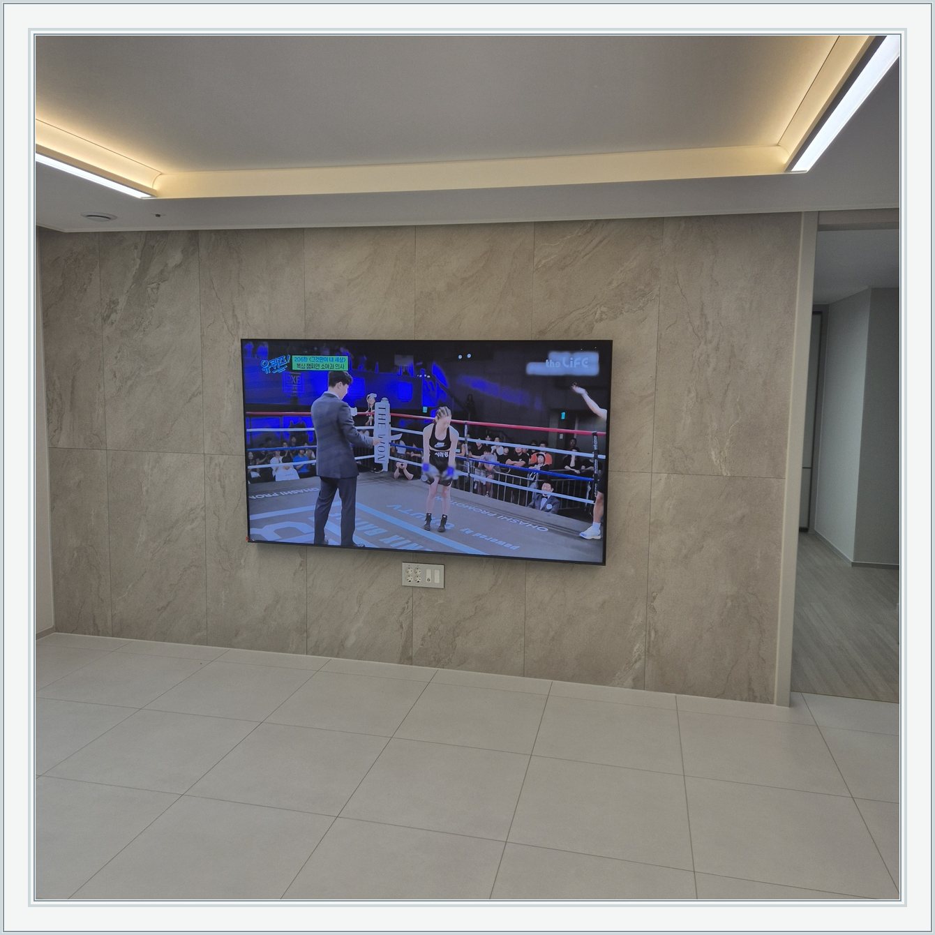 돌무늬 패널과 대형 TV / TV 아래 콘센트 패널이 드러나는 구도입니다