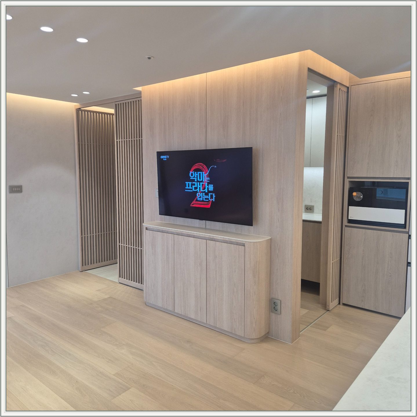 세로 원목 패널 위에 걸린 TV와 수납장 / 격자 형태 파티션을 끼고 TV가 놓인 위치를 확인할 수 있습니다