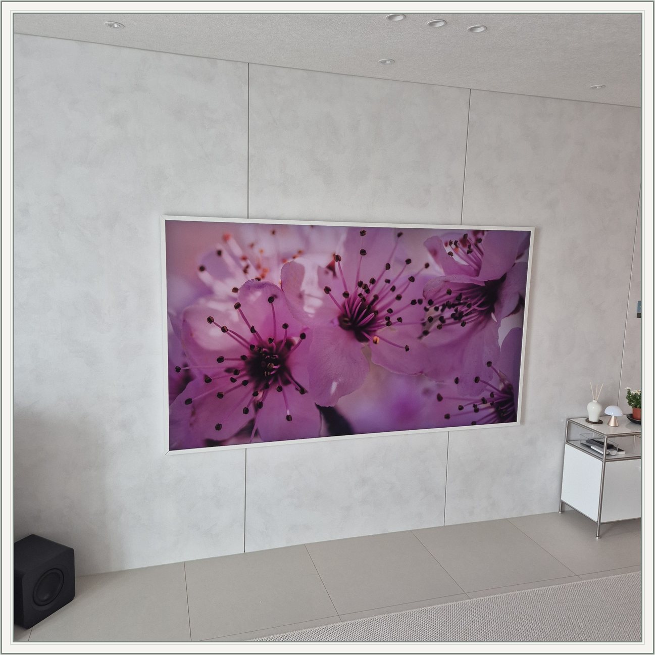 꽃 화면이 나오는 흰색 프레임 TV / 밝은 패널 위 흰 테두리와 꽃 영상의 색 대비가 큽니다