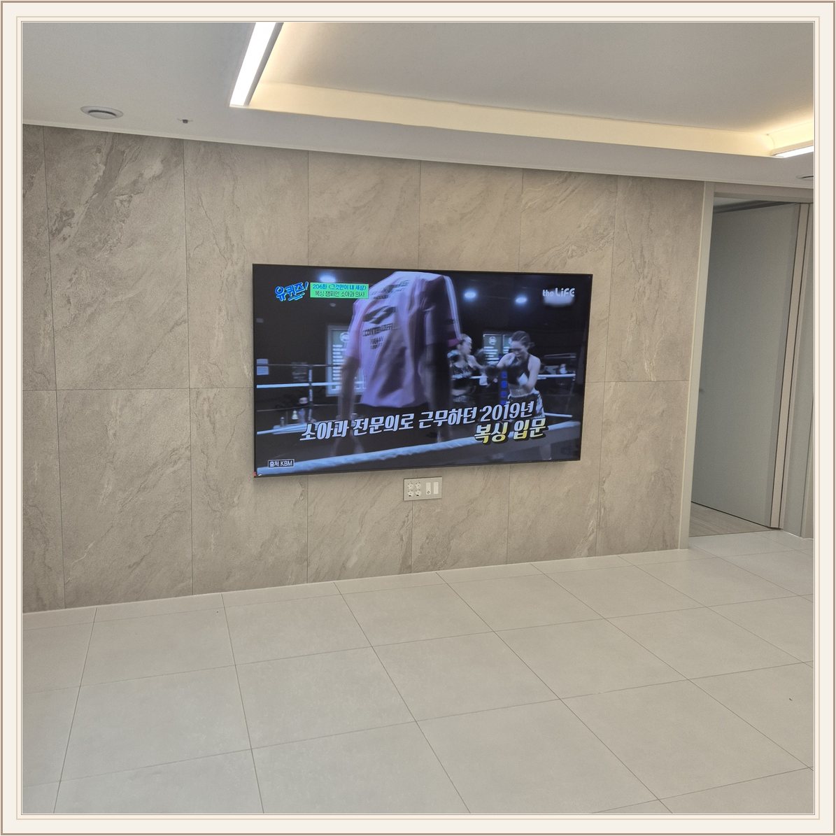 석재 느낌 벽면을 정면에서 본 TV / 벽 마감의 세로 이음선이 TV 양옆에 남아 있습니다